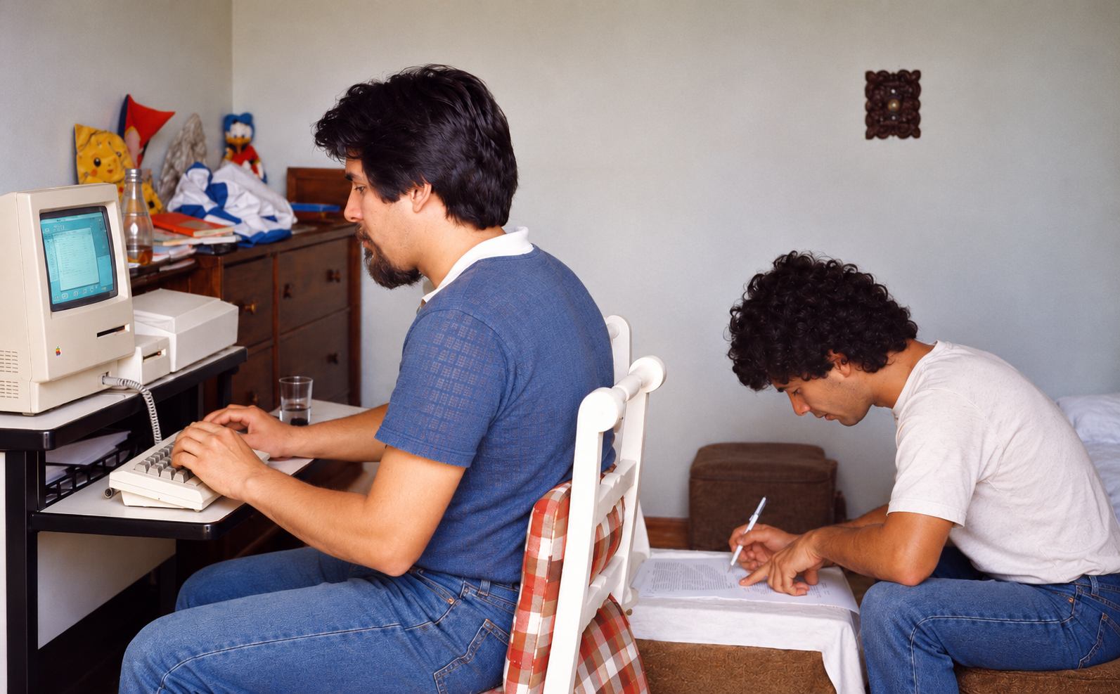 Aníbal Carmona escribiendo en una Macintosh y Eric Lattanzi tomando notas sobre papeles, trabajando en la tesis en 1986